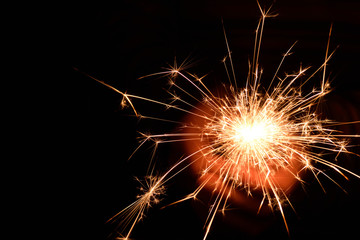 Fototapeta premium Blank background with bengal fire .Sparkler . New year party sparkler on black background A man holds a burning Bengal flame in his hands