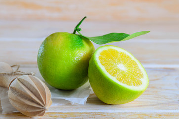 Whole green orange with leaves and green orange cut in half on wooden background. This is typical citrus fruit on Canary Islands and Vietnam.