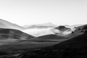 View of Castelluccio di Norcia (Umbria) at dawn, with mist, big meadows and totally empty sky