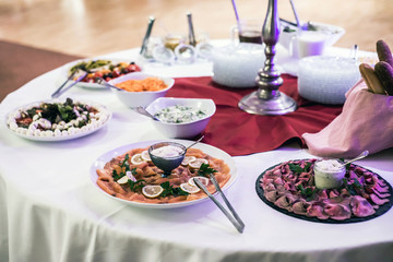 Variety of fresh salads bowls beef and salmon plates on buffet table business dinner