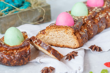 Traditional Greek Easter bread - tsoureki, sliced in Easter decoration with painted eggs and flowers.