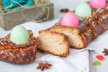 Traditional Greek Easter bread - tsoureki, sliced in Easter decoration with painted eggs and flowers.