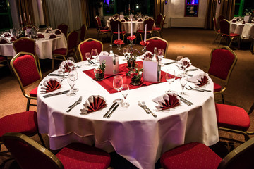 Banquet with red table setting tablecloth white dishes silver cutlery glasses and decorations white copy text space card