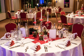 Banquet with red table setting tablecloth white dishes silver cutlery glasses and decorations white copy text space card