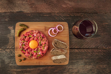 Overhead photo of steak tartare with garnish, wine, and copyspace