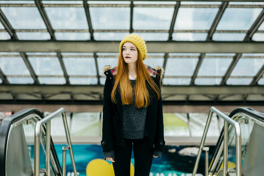 Young redhead woman standing and looking away in mall