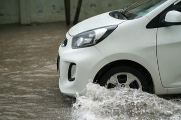 Car splashes through a large puddle on a flooded street