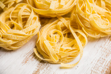 Pasta nests on the rustic wooden background. Selective focus.