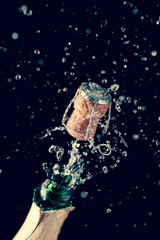 Opening bottle of champagne on empty black background