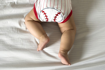 A baby in prone position while wearing a baseball clothing