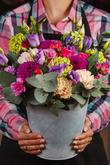 female hands holding a floral bouquet in a bucket