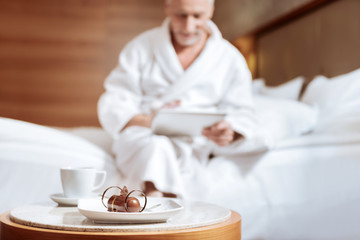 Chocolate cake. Selective focus of tasty breakfast placed on the coffee table with man posing on...