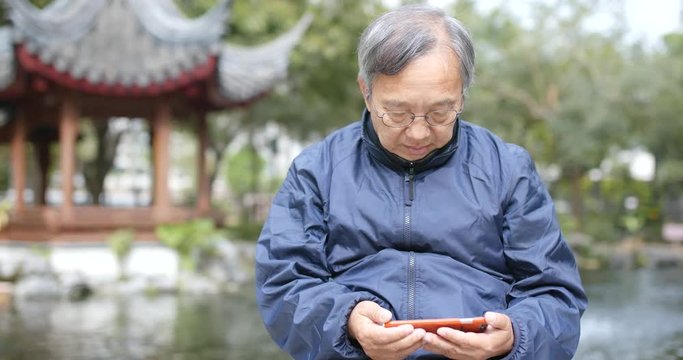 Senior man watching on smart phone in china