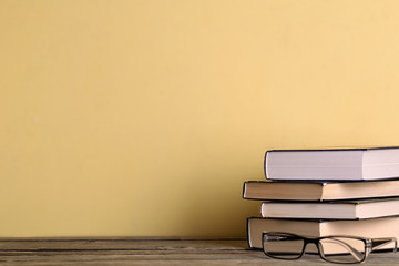   Group of school supplies and books on wooden table over a yellow  background