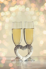 Two glasses with champagne and a white heart hand maid. Bokeh