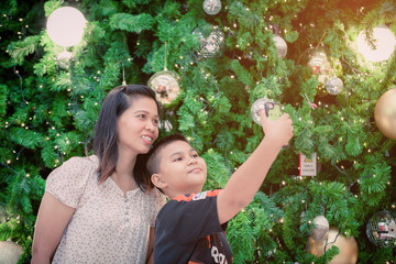 young mother and son taking a picture of them self at the christmas tree.