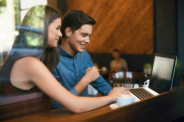 Beautiful Couple Working On Notebook In Cafe.