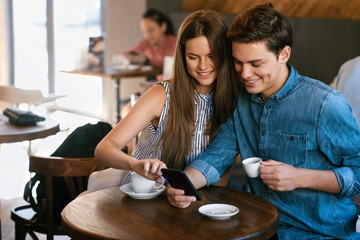 Obraz na płótnie Canvas Beautiful Couple In Cafe Using Phone