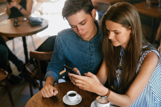 Beautiful Couple In Cafe Using Phone
