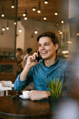 Man Talking On Phone And Drinking Coffee In Cafe.