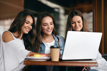 Girls In Cafe. Happy Friends Using Computer.