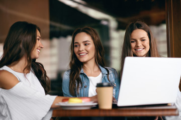 Girls In Cafe. Happy Friends Using Computer.