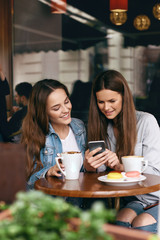 Happy Women Using Phone In Cafe.