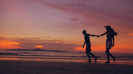 Silhouette of happy loving couple meet and play at the beach on sunset in ocean shore