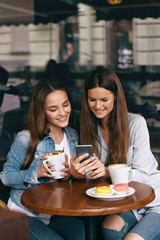 Happy Women Using Phone In Cafe.