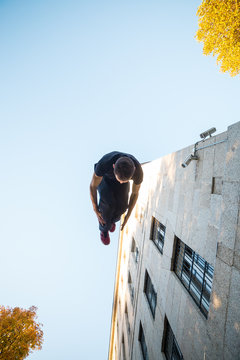 Young man doing a side flip or somersault while practicing parkour on the street. 