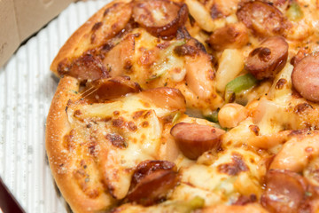 Close up of pizzas with variety of toppings and cheese in cardboard take out boxes with open lid