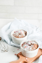 Valentine's day chocolate mug cake or brownie with powdered sugar and sweet heart shaped sprinkles, white table background, copy space top view