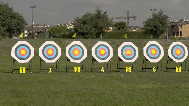 Numbered targets set for an archery competition in a wide green park.