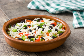 Traditional cuban rice, black beans and pepper on wooden table background. Moros y cristianos.