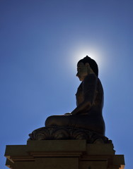 Buddha Dordenma statue silhouette on blue sky background with sun halo around its head in Thimphu, Bhutan