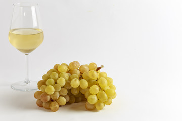 Grappolo di uva bianca con bicchiere di vino