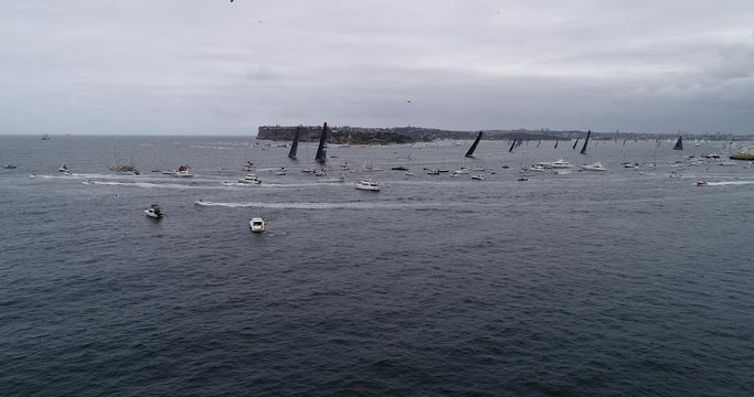 Sydney – Hobart Yacht race Leaders clearing from Sydney Harbour against South Head, surrounded by boats and yachts of public.
