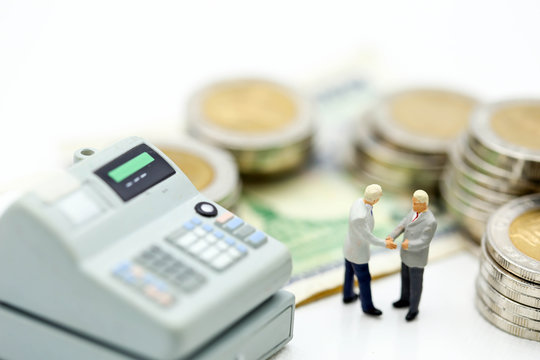 Miniature people, businessman handshake  standing with calculator and coins money, tax, financial and business concept.