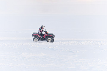 man driving a quad bike in the winter field