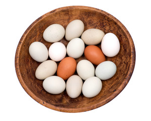 Unwashed fresh organic gmo and soy free pasture raised chicken eggs in wooden bowl isolated on white background