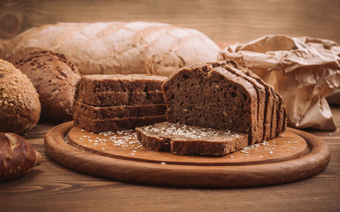 Photo of many mixed baked breads on rustic wooden table