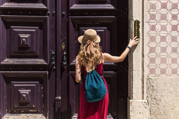 Woman knocking and ringing to the big wooden door