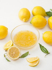 Fototapeta na wymiar Fresh lemons with leaves and chopped lemons and sugar in a bowl on a white background.