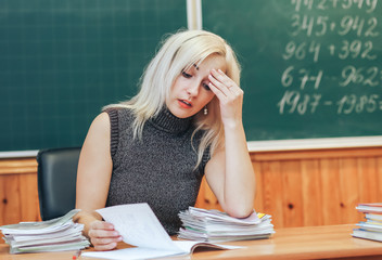 female teacher. Fatigue at work, holding his head with his hands. The concept of the hard work of...