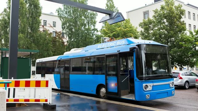 Electric bus at a stop is charged by wireless induction charging, it's lights flash. 