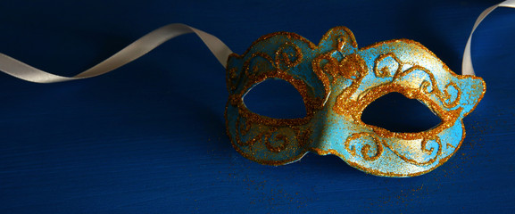 Image of elegant blue and gold venetian mask over blue background.