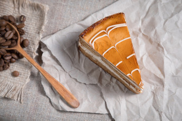 piece of cake with caramel lies on paper next to scattered coffee beans