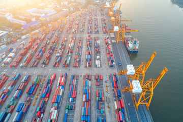 Containers yard shot from drone in port congestion with ship vessels are loading and discharging operations of the transportation in international port.