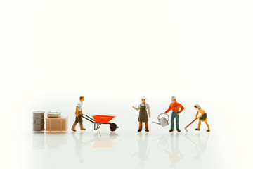 Miniature people, gardener in action isolated on white background, using as agriculture concept - Vintage filter