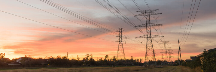 Industrial background group silhouette of transmission tower (or power tower, electricity pylon, steel lattice tower) at bloody red sunset. Texture of high voltage pillar, overhead power line panorama